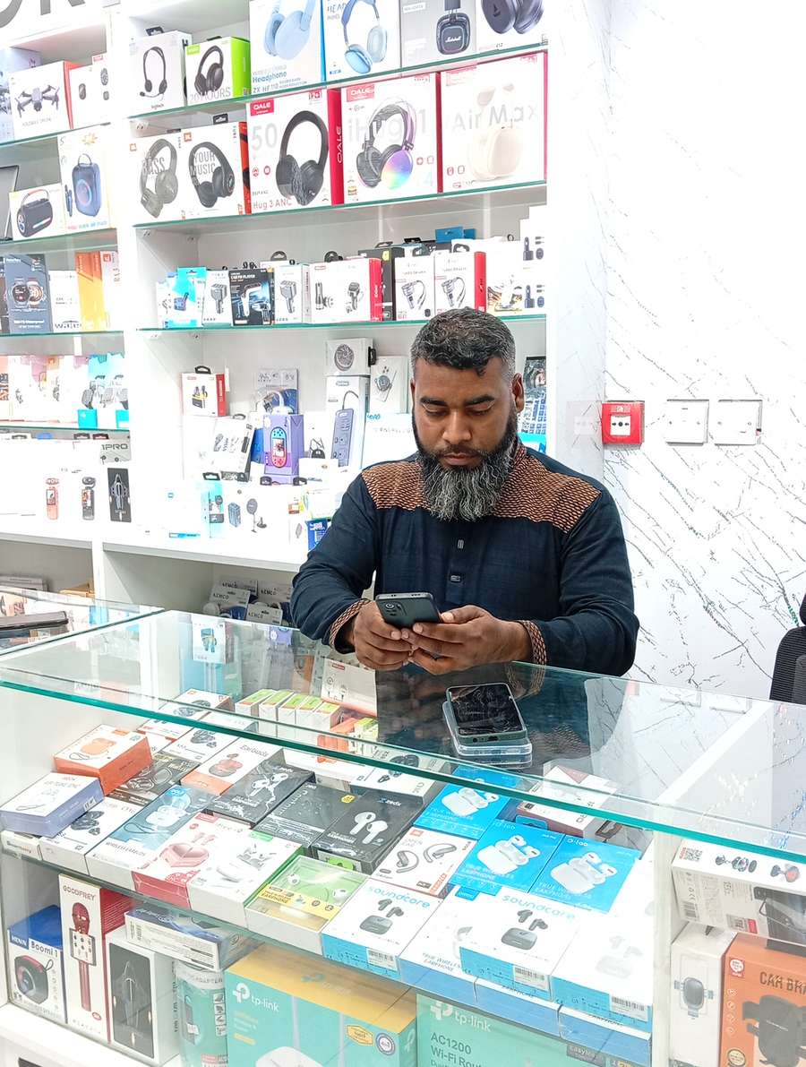 Behind the counter at Al Mashhoor Al Jadeed, with headphones and accessories on the wall